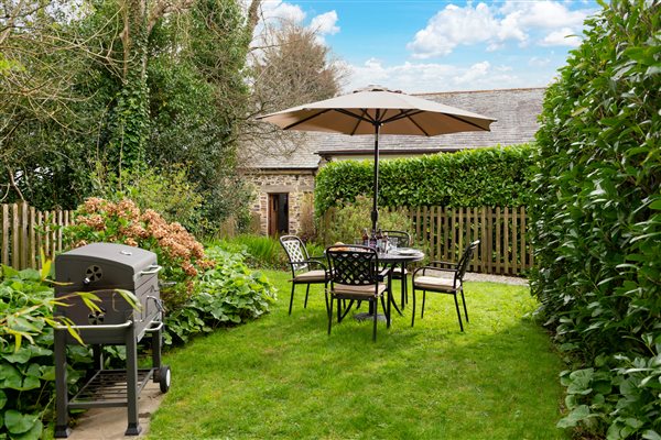 Garden with lawn, shrubs and hedging with BBQ and garden furniture
